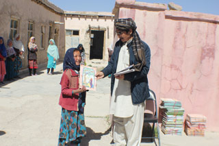 A girl receiving a Hoopoe book during a Books for Afghanistan distribution in Ghazni